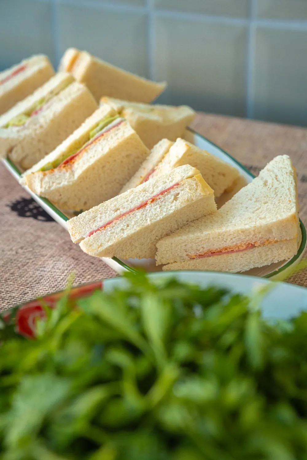 Platter of triangle sandwiches with fresh leaves