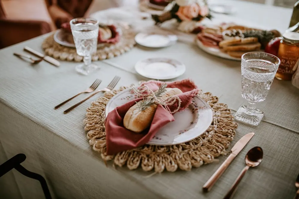 Wedding table set with a bread roll tied in a pink napkin and rosemary