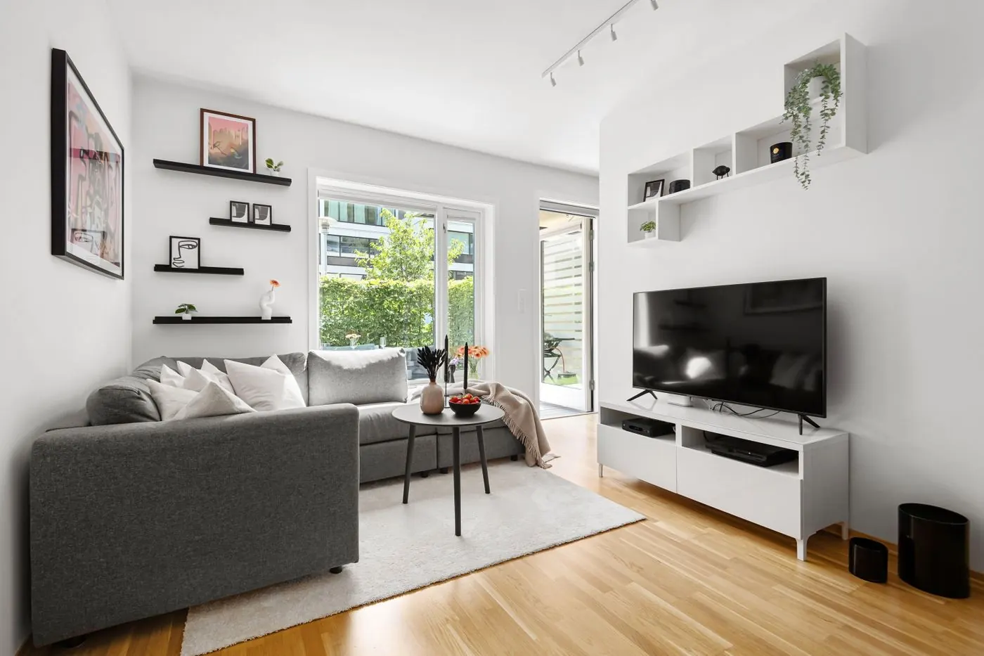 Bright living room with a wall-mounted TV above a white media unit