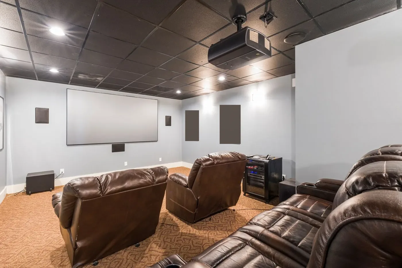 Home cinema with leather recliners, a large screen and a ceiling projector